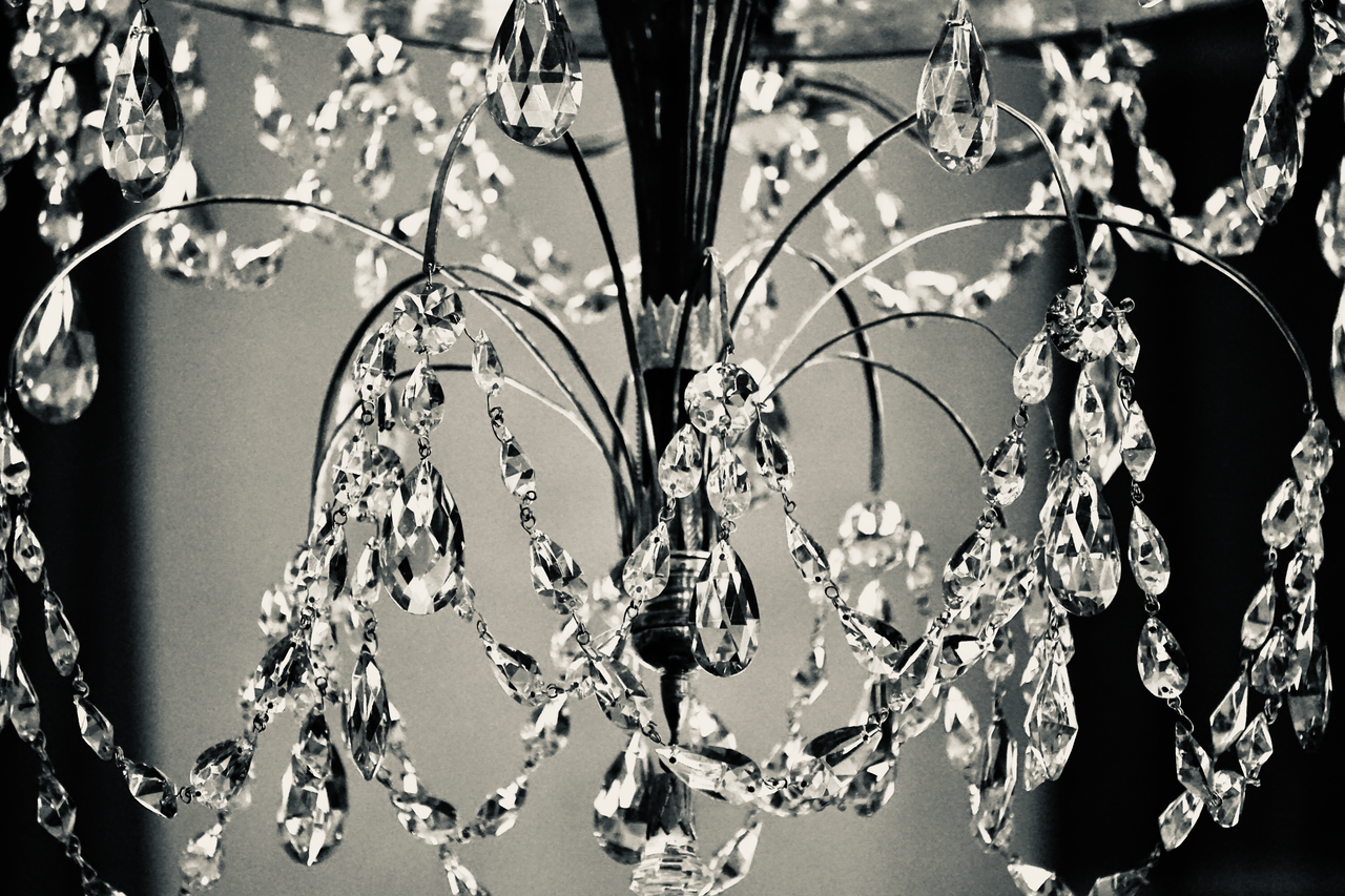 Graceful close-up of a crystal chandelier, capturing intricate details in black and white.