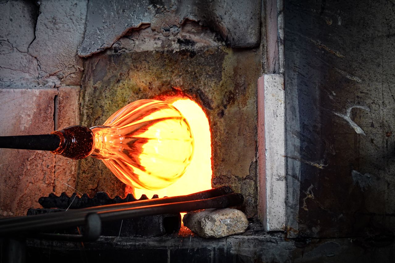 Close-up of glowing glass being shaped in a fiery glassblowing furnace.